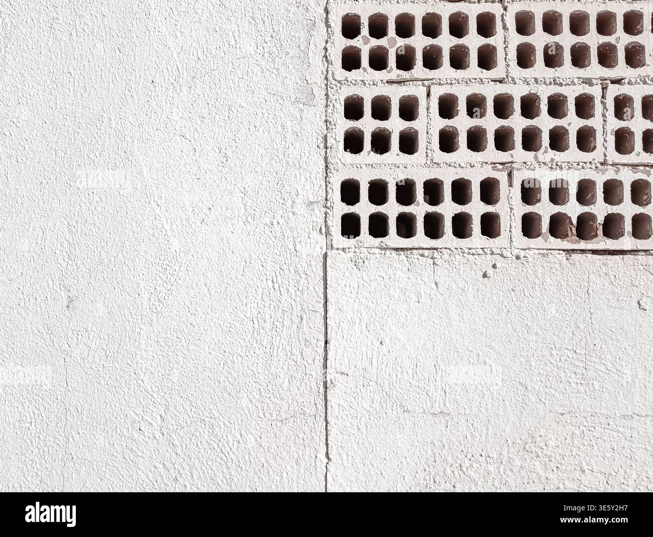 White Painted Wall with Exposed Perforated Bricks Stock Photo
