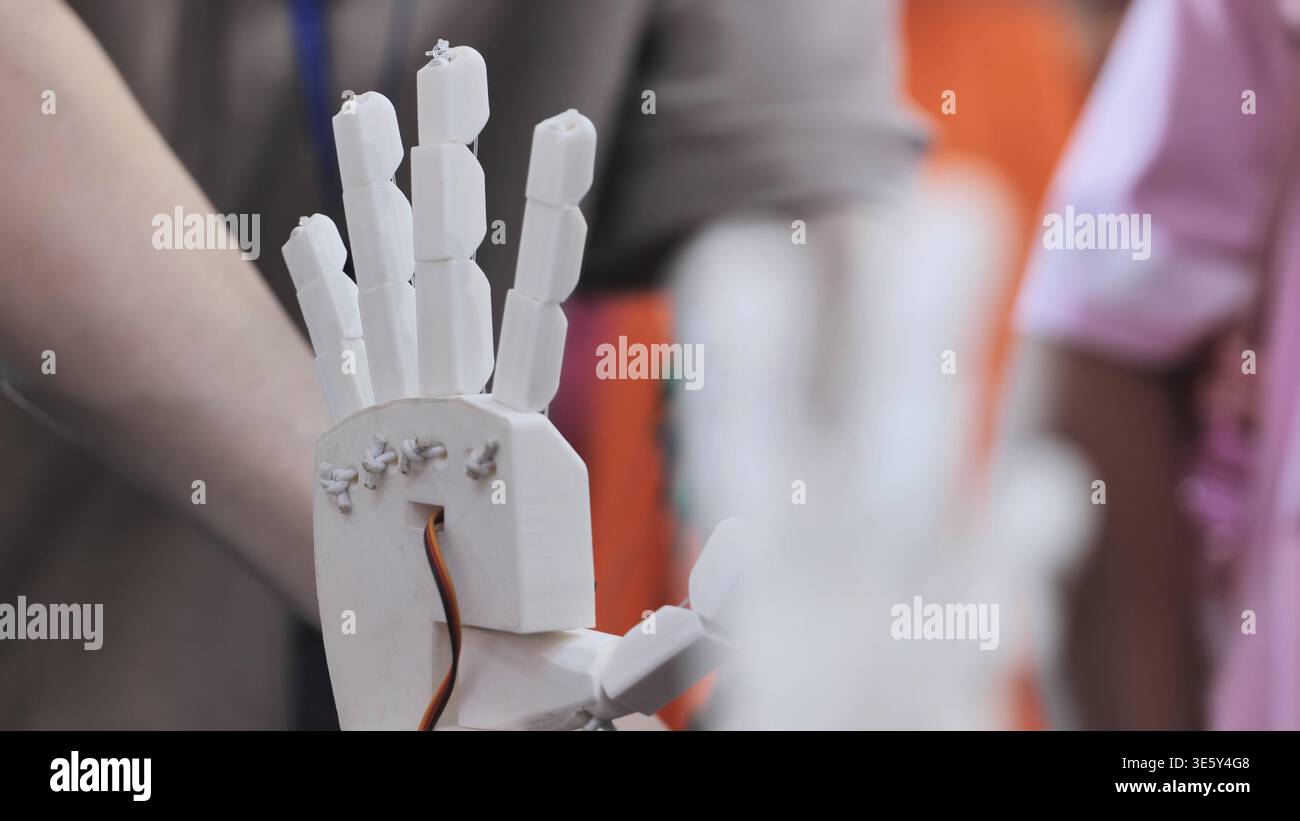 White 3D printed robotic hand prototype with wires and servo cable Stock Photo
