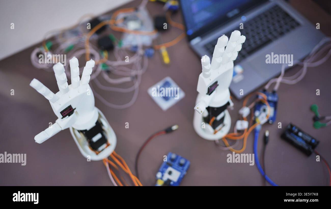 Robotic hands and electronic components on a workbench with a laptop Stock Photo