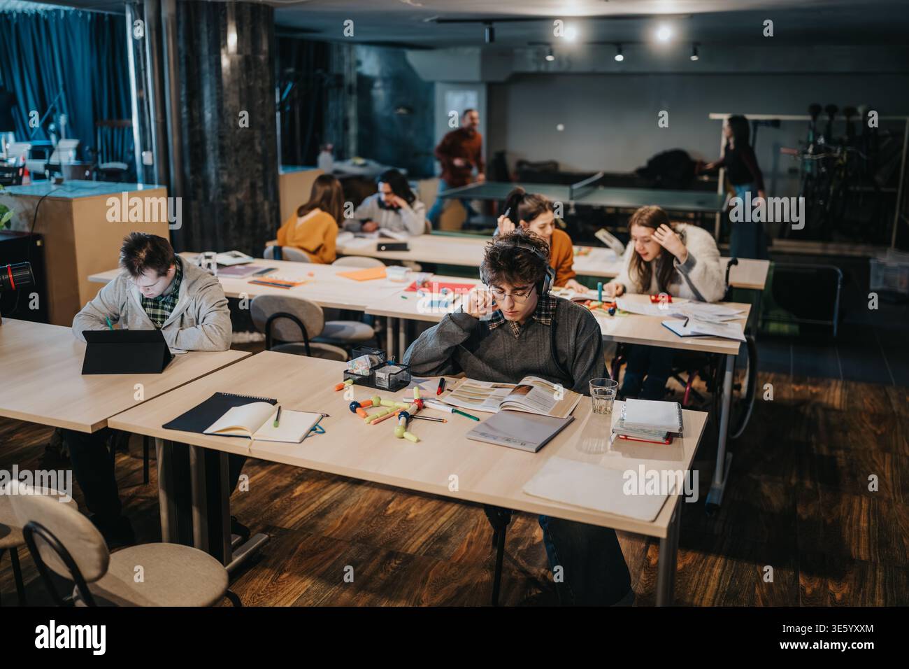 Students studying together in a modern shared study space with books and laptops Stock Photo