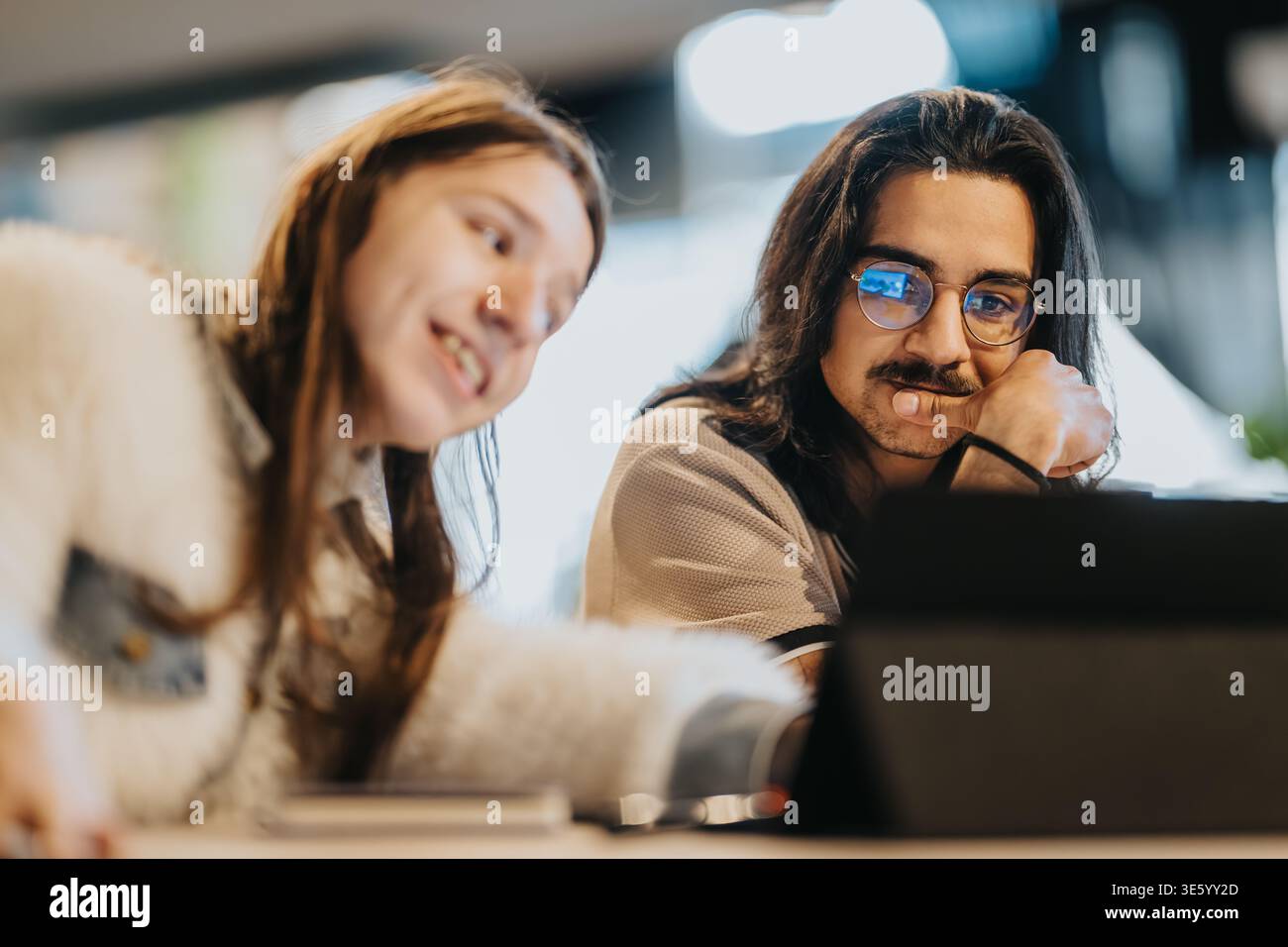 Two young people collaborating over a laptop in a casual study session Stock Photo