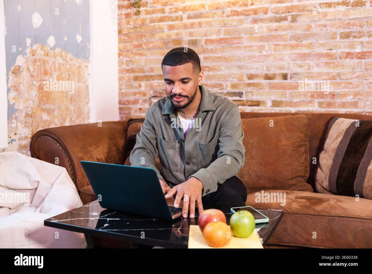 Focused young man working from home sitting on couch using laptop Stock Photo
