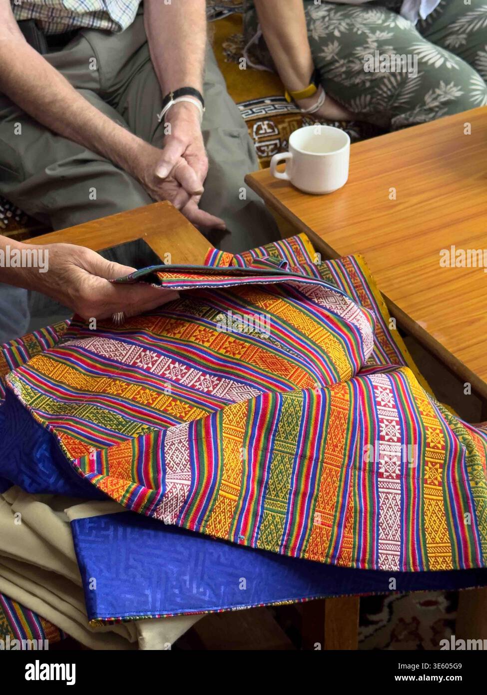 Bhutanese woman showing group of tourists some national clothes garments she has woven on her loom. - Smartphone Captured Stock Image