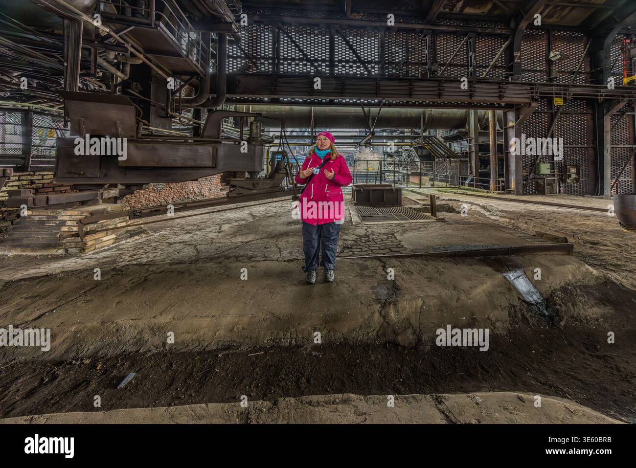 Tour guide Manuela Sass at the tapping point of Blast Furnace No. 5. It was the last and most modern blast furnace at the Thyssen steelworks in Meiderich. It came into operation in 1973 and produced special pig iron from ore at temperatures of up to 2,000 °C – as a feedstock for Thyssen’s steelworks. It was the last to be shut down on 4 April 1985, after only 12 years, due to crises in the steel market. Manuela Sass as a tour guide at Landschaftspark Duisburg-Nord (Duisburg-Nord Landscape Park). Duisburg, North Rhine-Westphalia, Germany Stock Photo