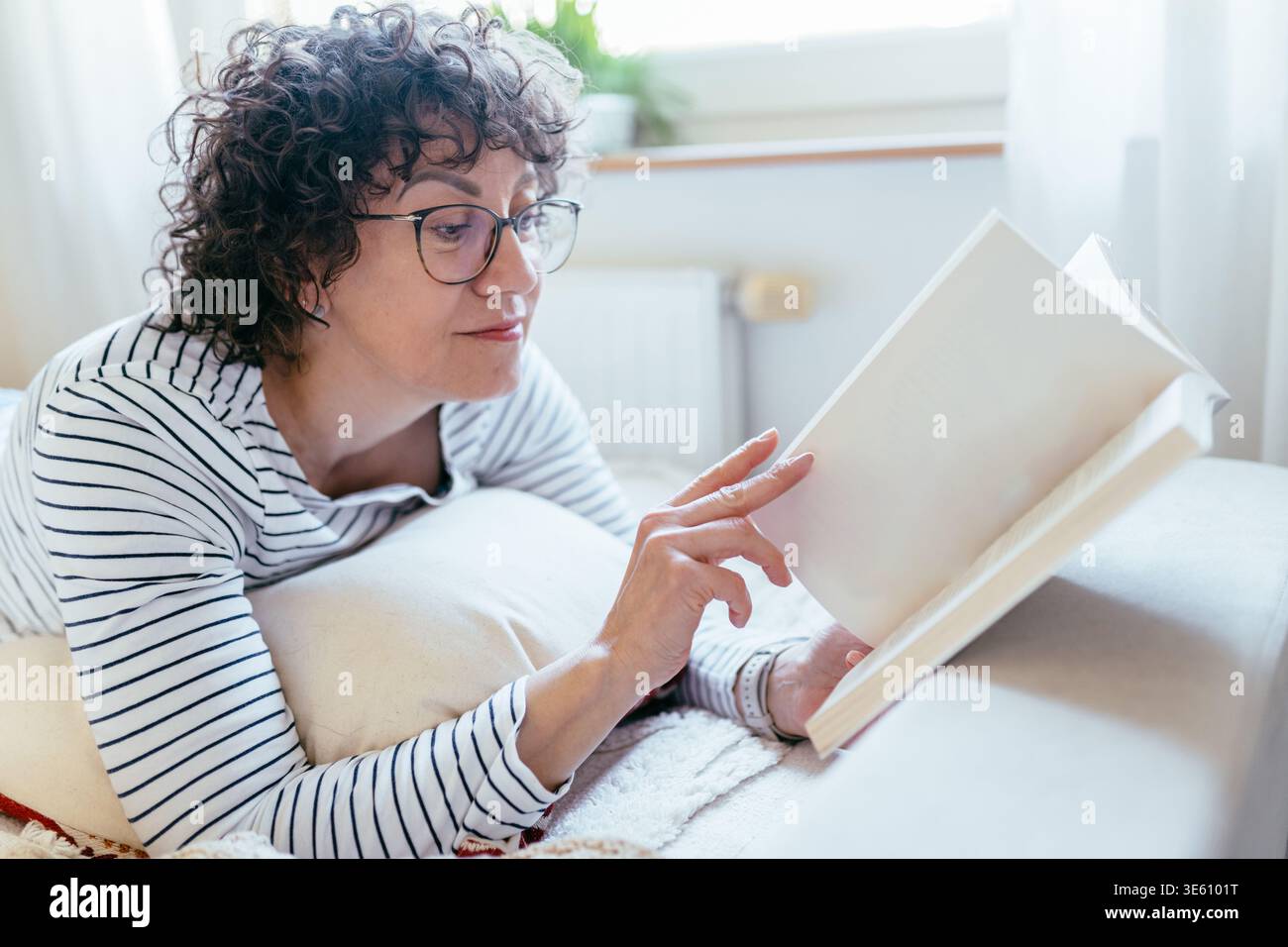 Close up female reading book while lying on bed at home Stock Photo