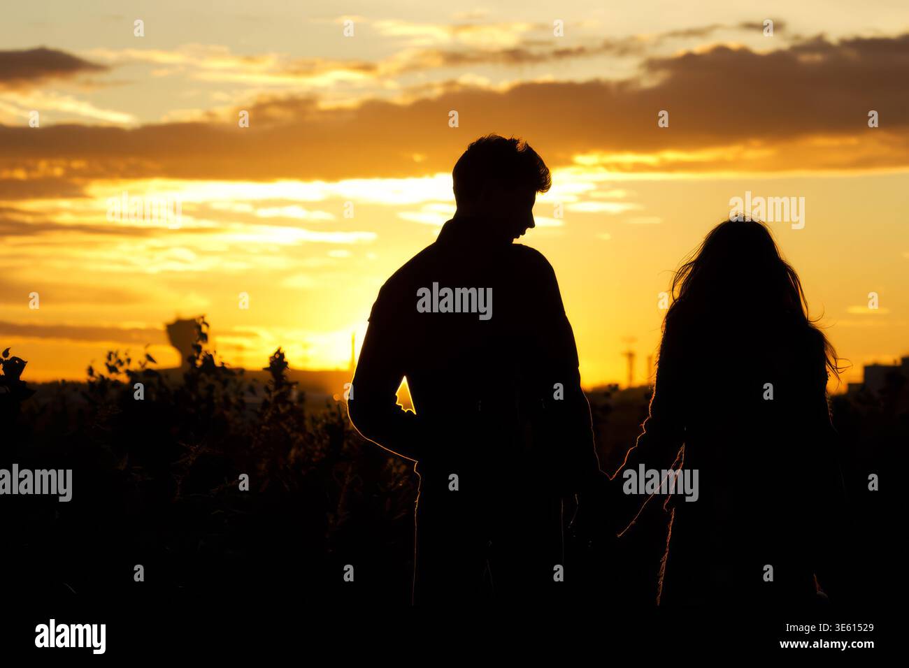 Silhouette of romantic couple holding hands at sunset Stock Photo