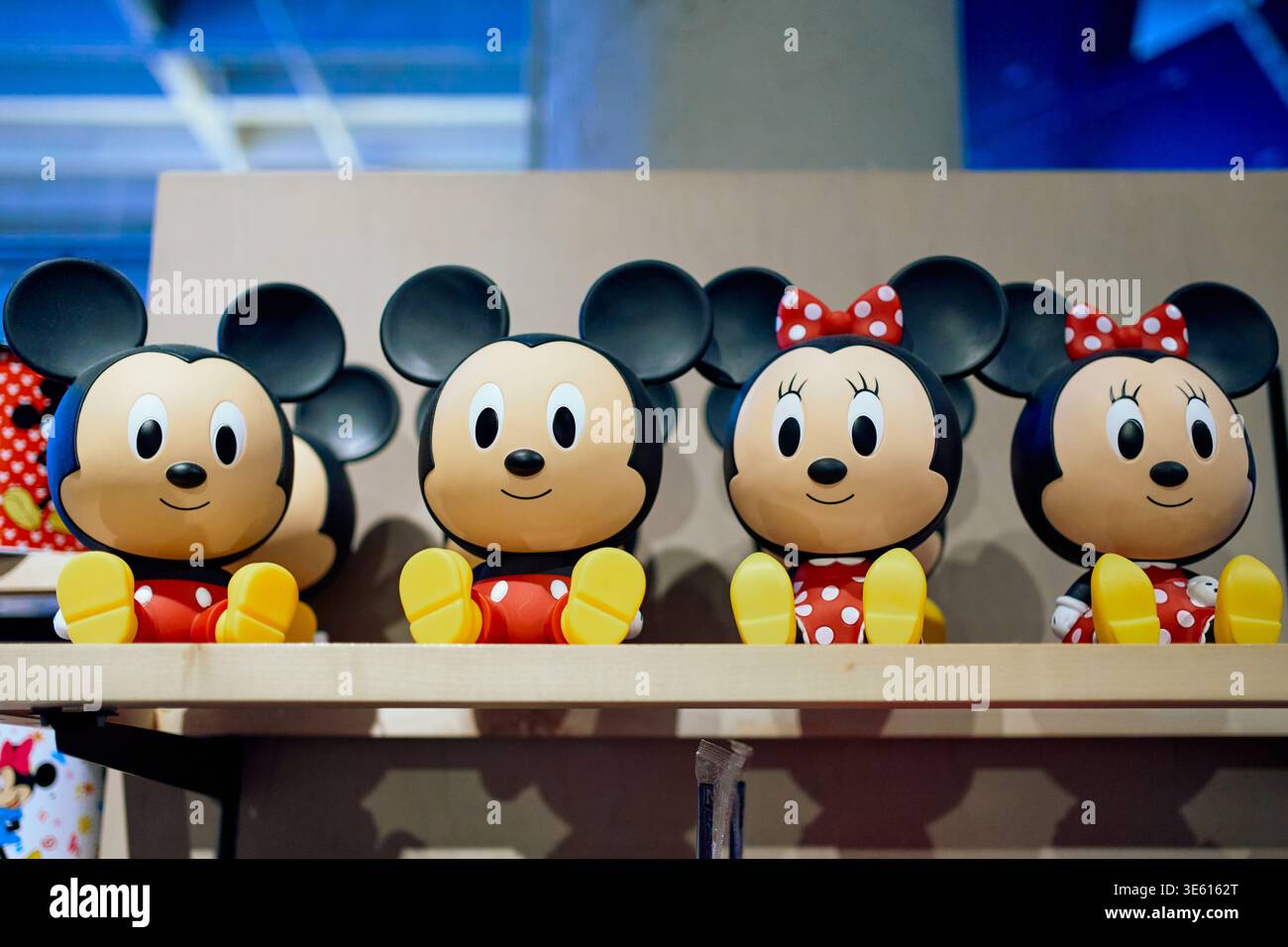 Mickey and Minnie Mouse stylized plastic figurines sitting on a shelf in a souvenir shop. Colorful Disney character toys and retail display. Stock Photo