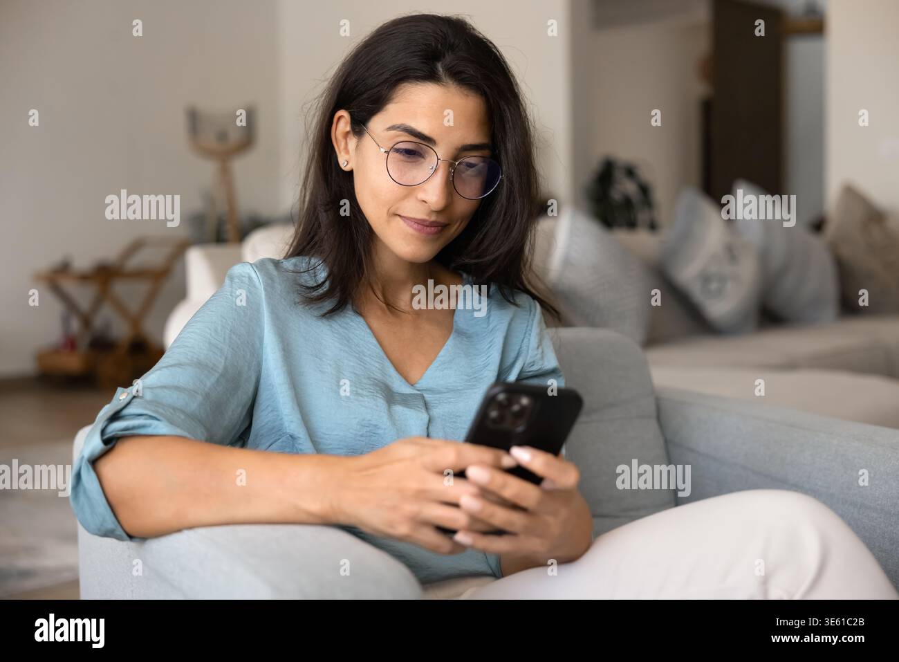 Young Brazilian woman in eyeglasses using smartphone Stock Photo