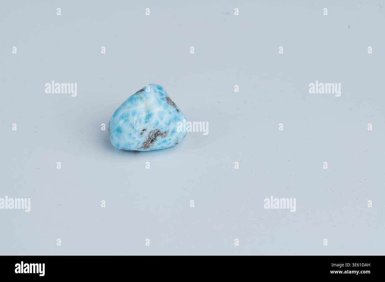 A blue and white Larimar gemstone sits on a flat, light surface. Stock Photo