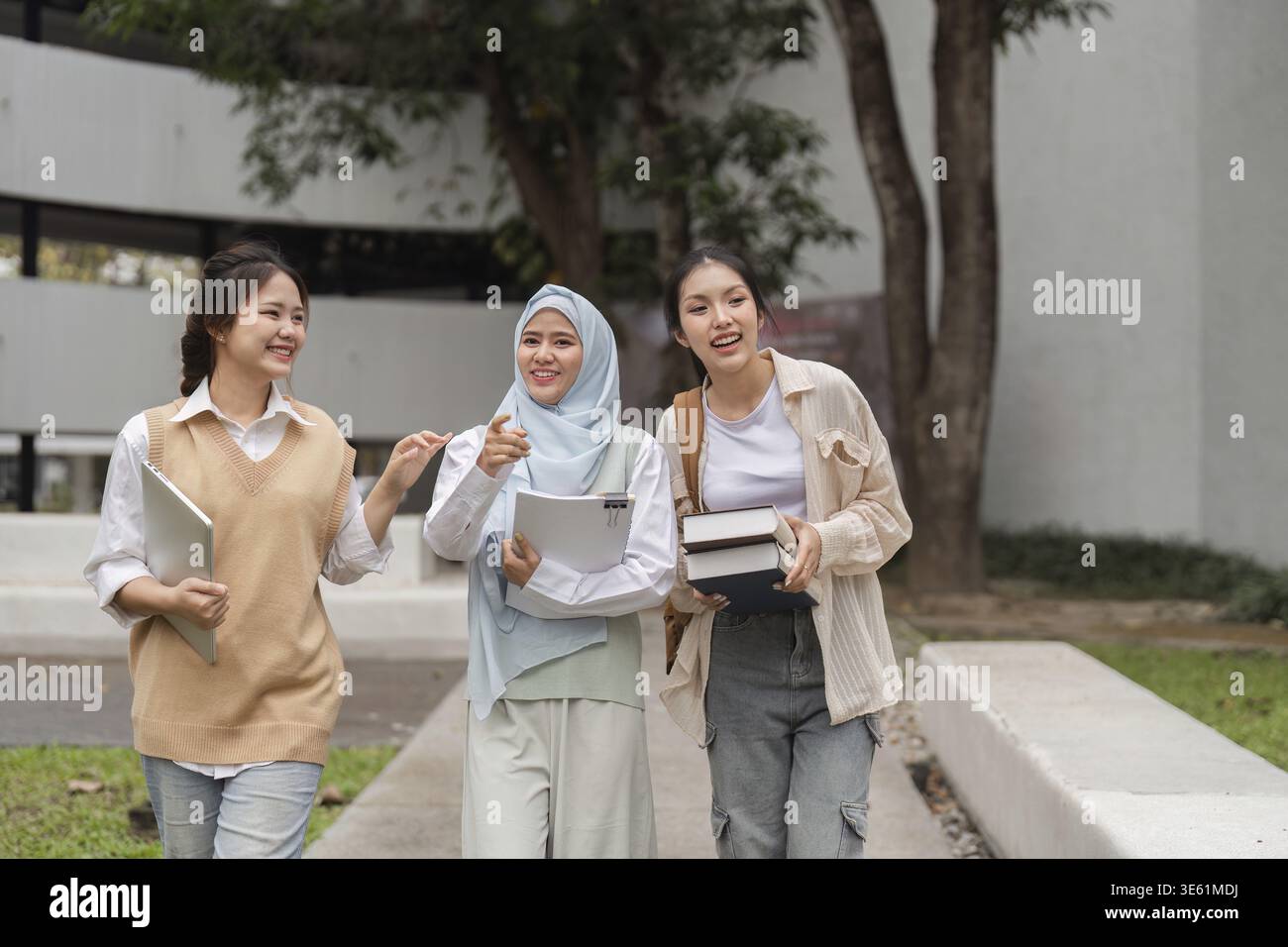 A group of diverse university students walking together and engaging in cheerful conversation while enjoying their time on campus Stock Photo
