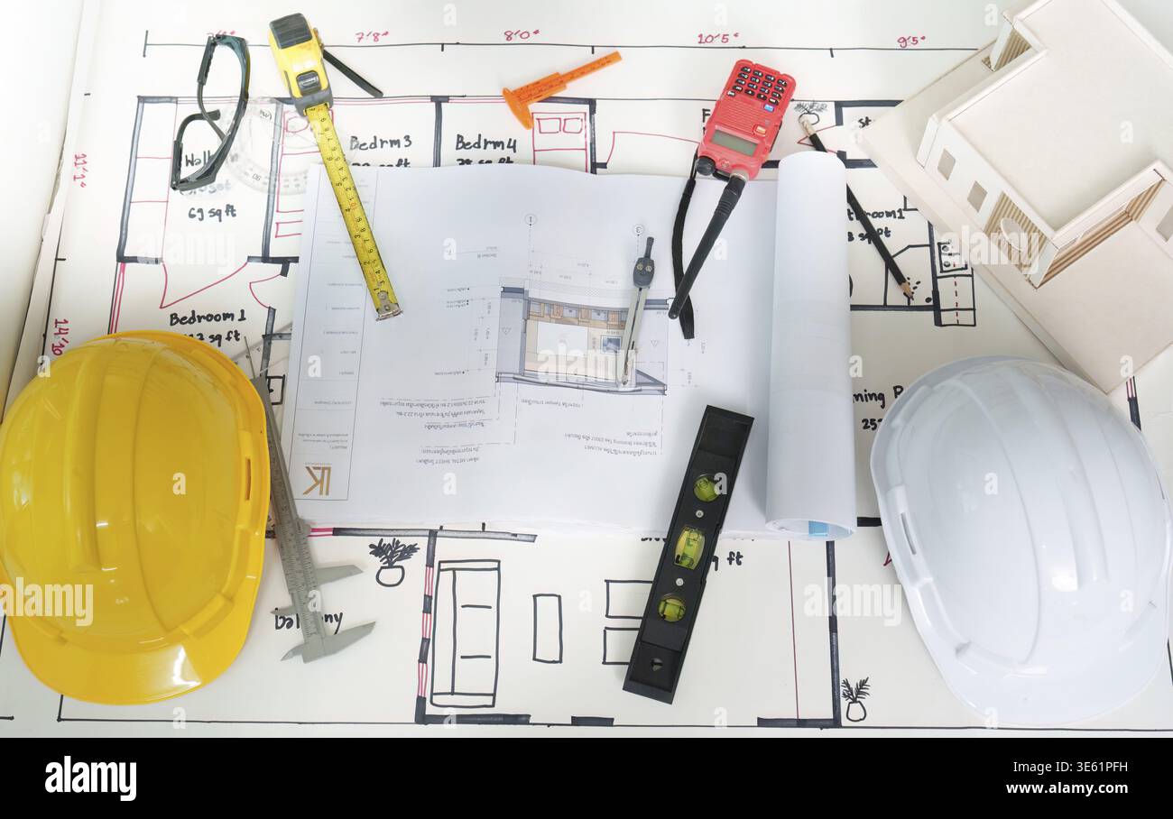 Detailed construction plans, hard hats, and tools laid out on a table ...