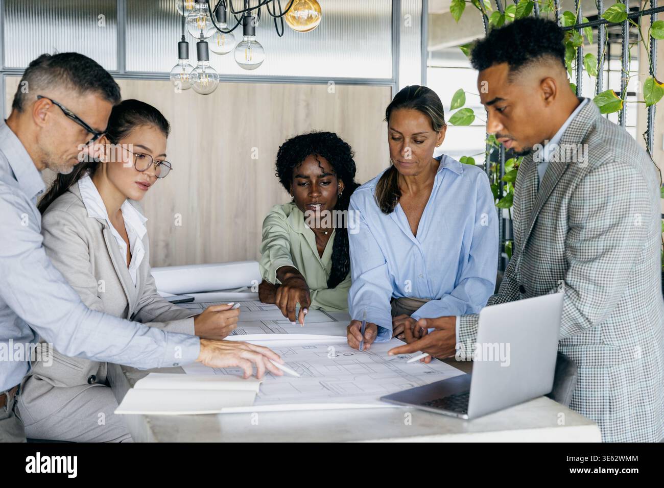 Black structural engineer explaining technical details to white and asian Stock Photo