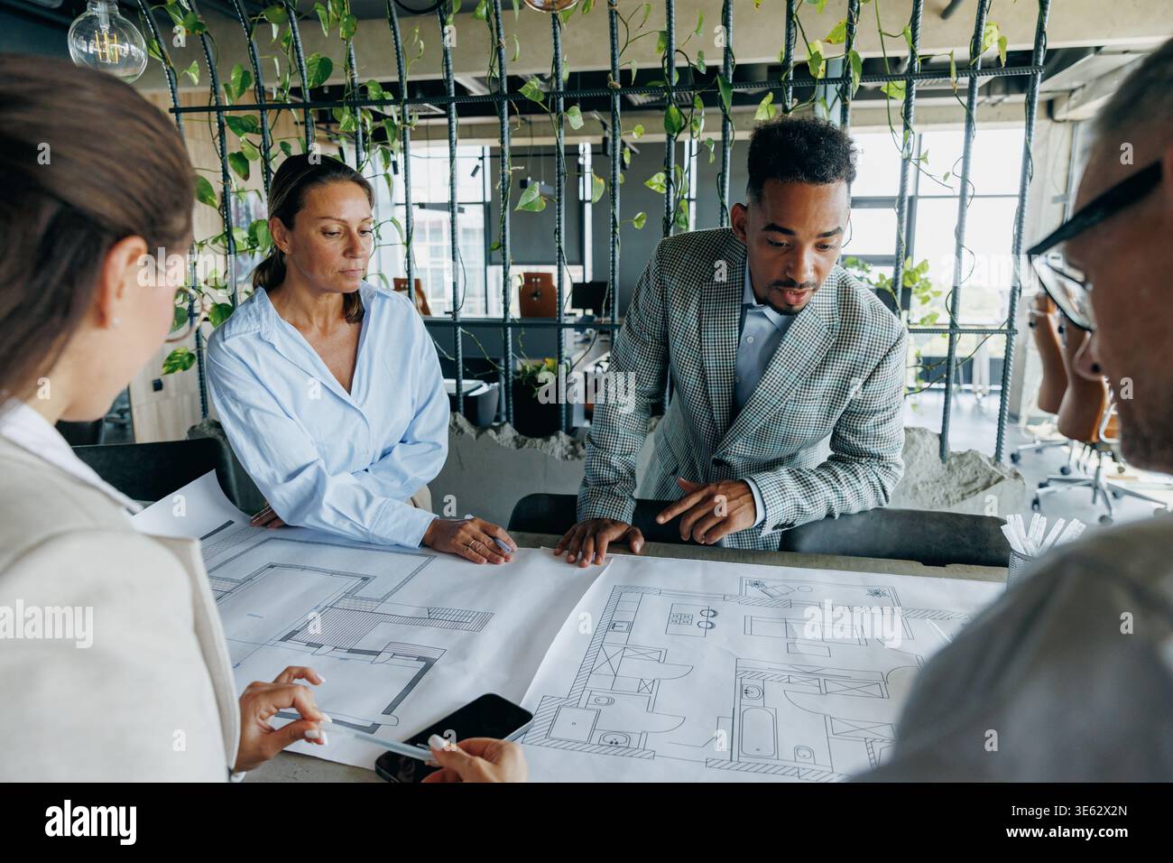 Multiracial architects examining construction plans together Stock Photo