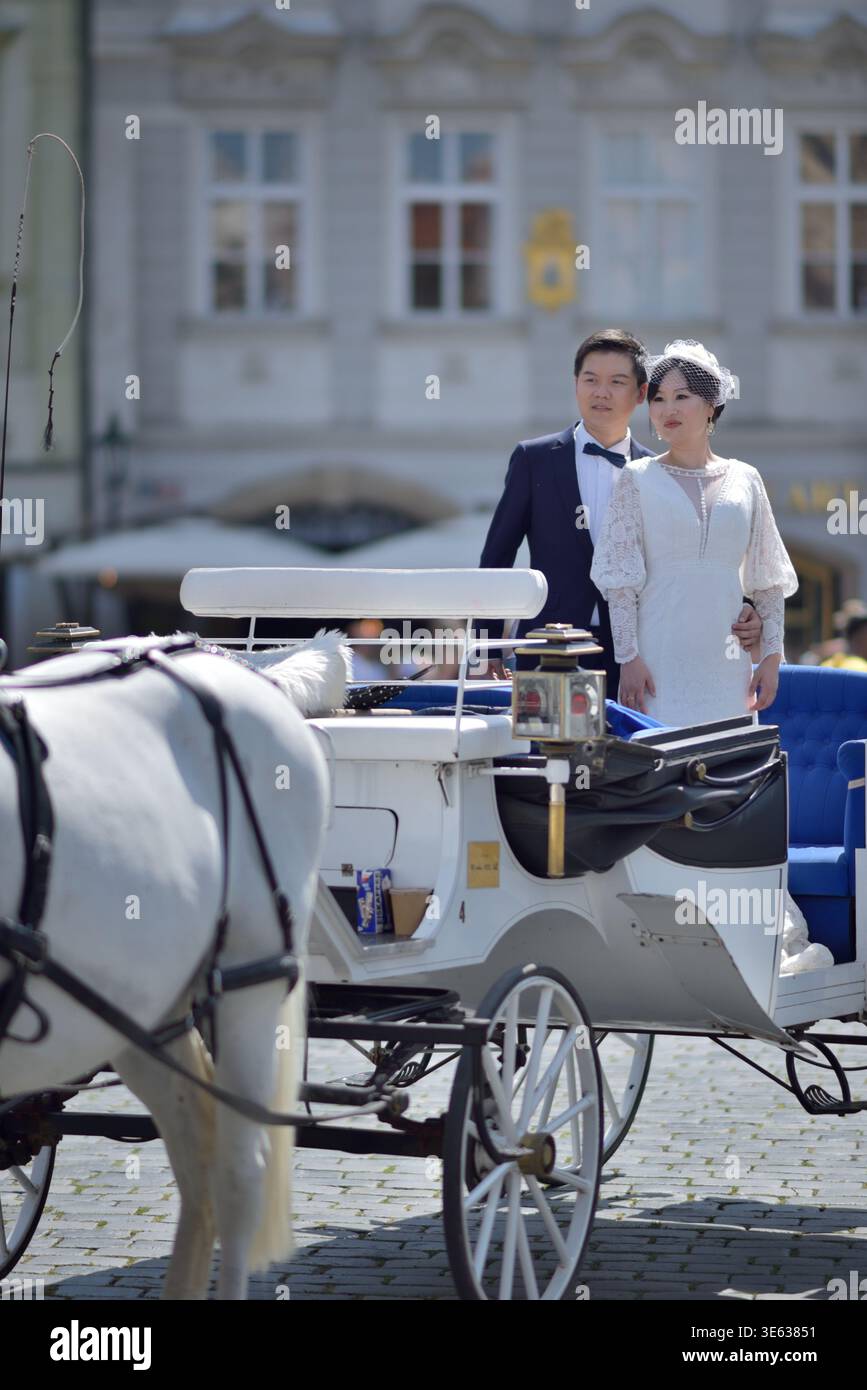 Bride and groom standing in a white horse-drawn carriage on a cobblestone square in Old town of Prague, Czech Republic on 12 August 2024 Stock Photo