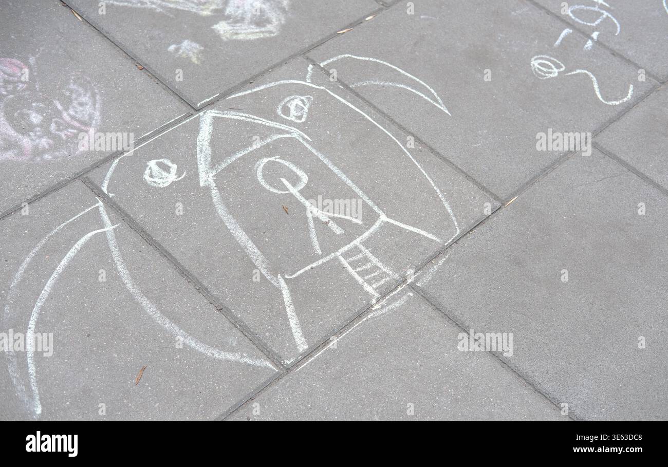 Chalk drawing of abstract face is sketched on a paved sidewalk surface outdoors Stock Photo