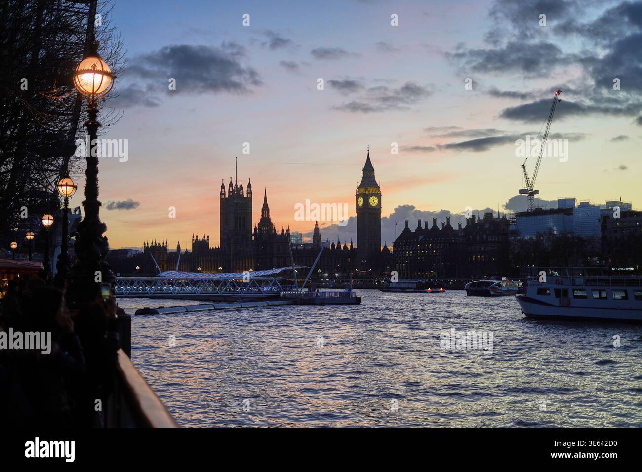 A scenic view of the River Thames in London at sunset, featuring the iconic silhouette of Big Ben (Elizabeth Tower) and the Houses of Parliament Stock Photo