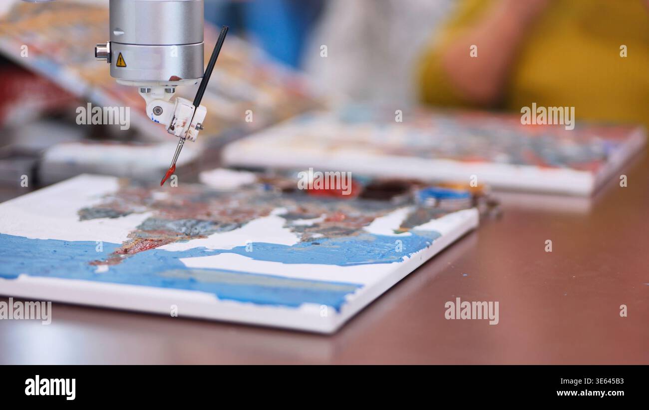 Robot arm holding a paintbrush creating an abstract artwork, exploring AI creativity Stock Photo