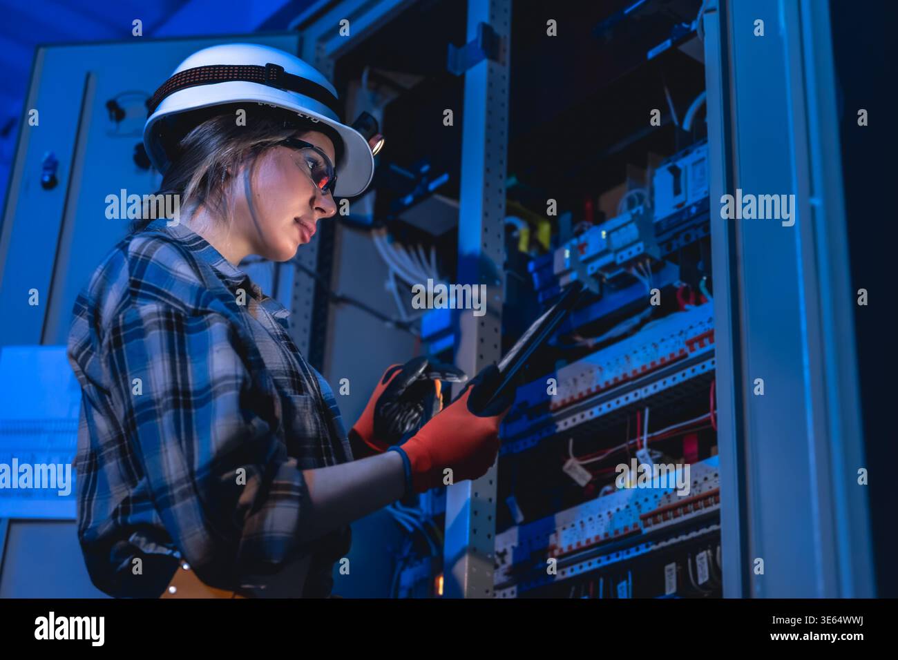 Female engineer inspecting electrical network using tablet. Technical control. Stock Photo