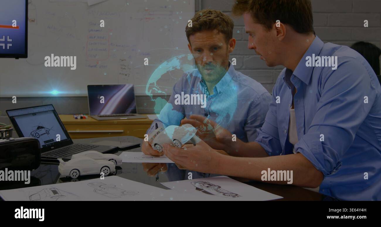 Holding white scale car, two designers wearing blue shirts examining model in studio with AR globe Stock Photo