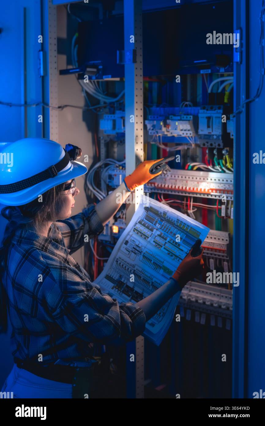 Electrical specialist inspecting equipment using power system blueprint. Technical maintenance. Stock Photo