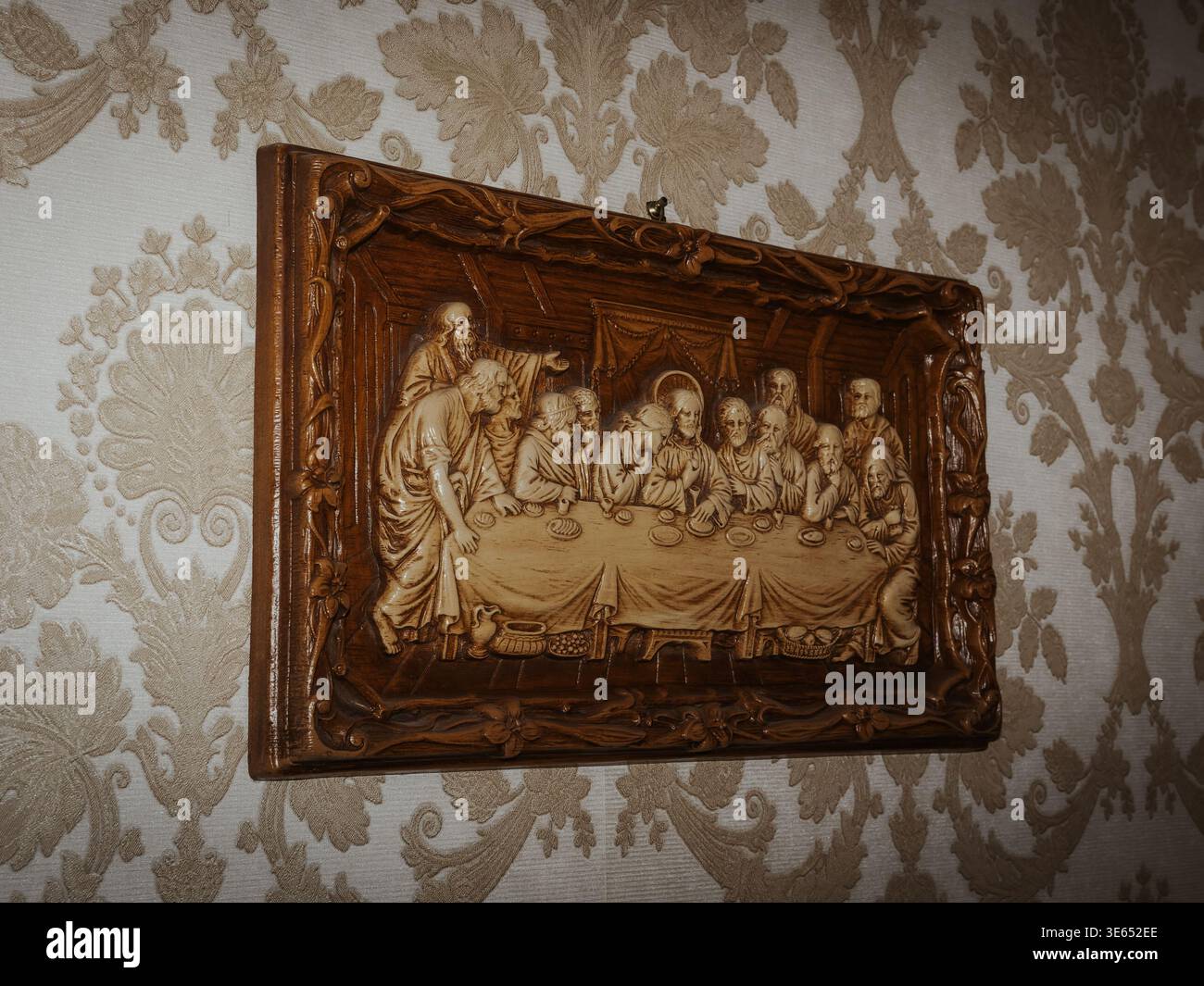 Carved wood religious relief showing Jesus and the 12 apostles at The Last Supper on a patterned wall Stock Photo