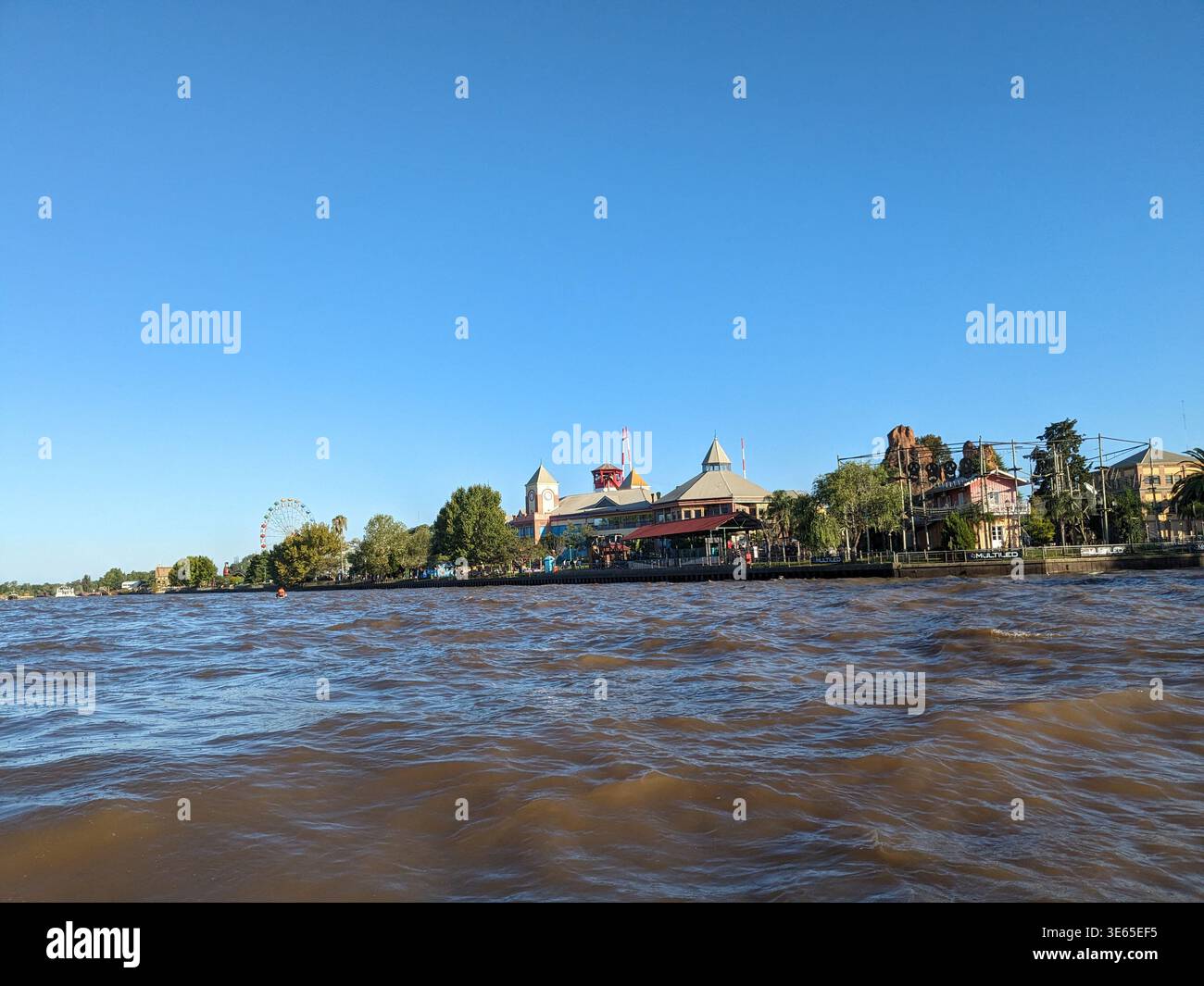 Distant view of Parque de la Costa amusement park from the Luján River, Tigre, Argentina, under a clear blue sky. - Smartphone Captured Stock Image