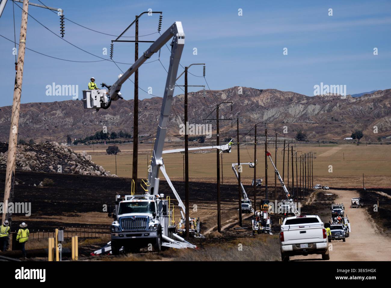 Utility crews work to restore power lines in an area burned by the ...