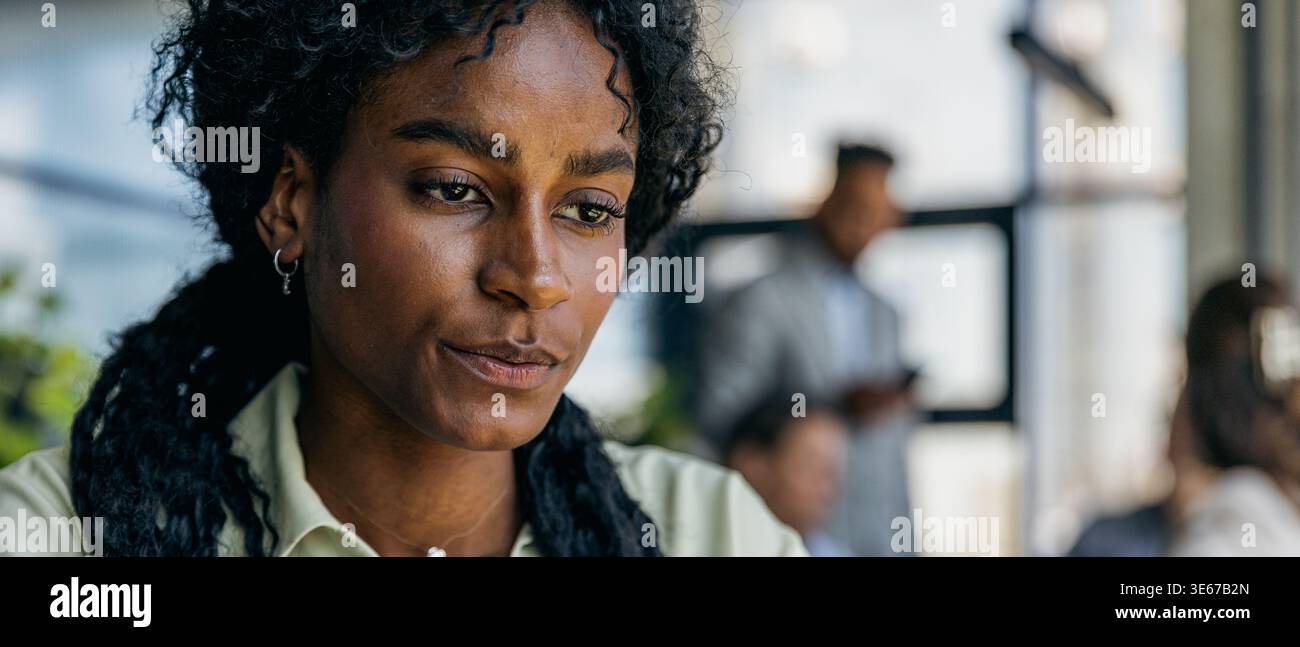 Focused female professional analyzing building layouts in open workspace Stock Photo