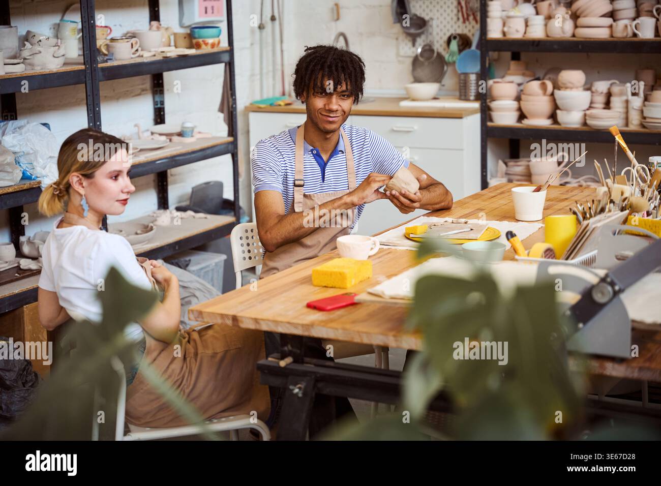 Young adults working with clay in pottery studio during daytime Stock Photo