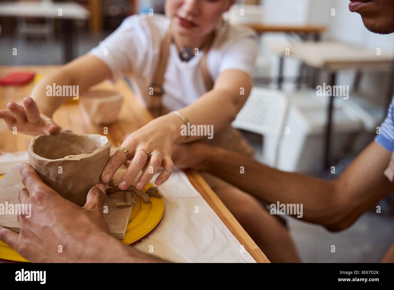 Two adults creating pottery in art studio during daytime Stock Photo