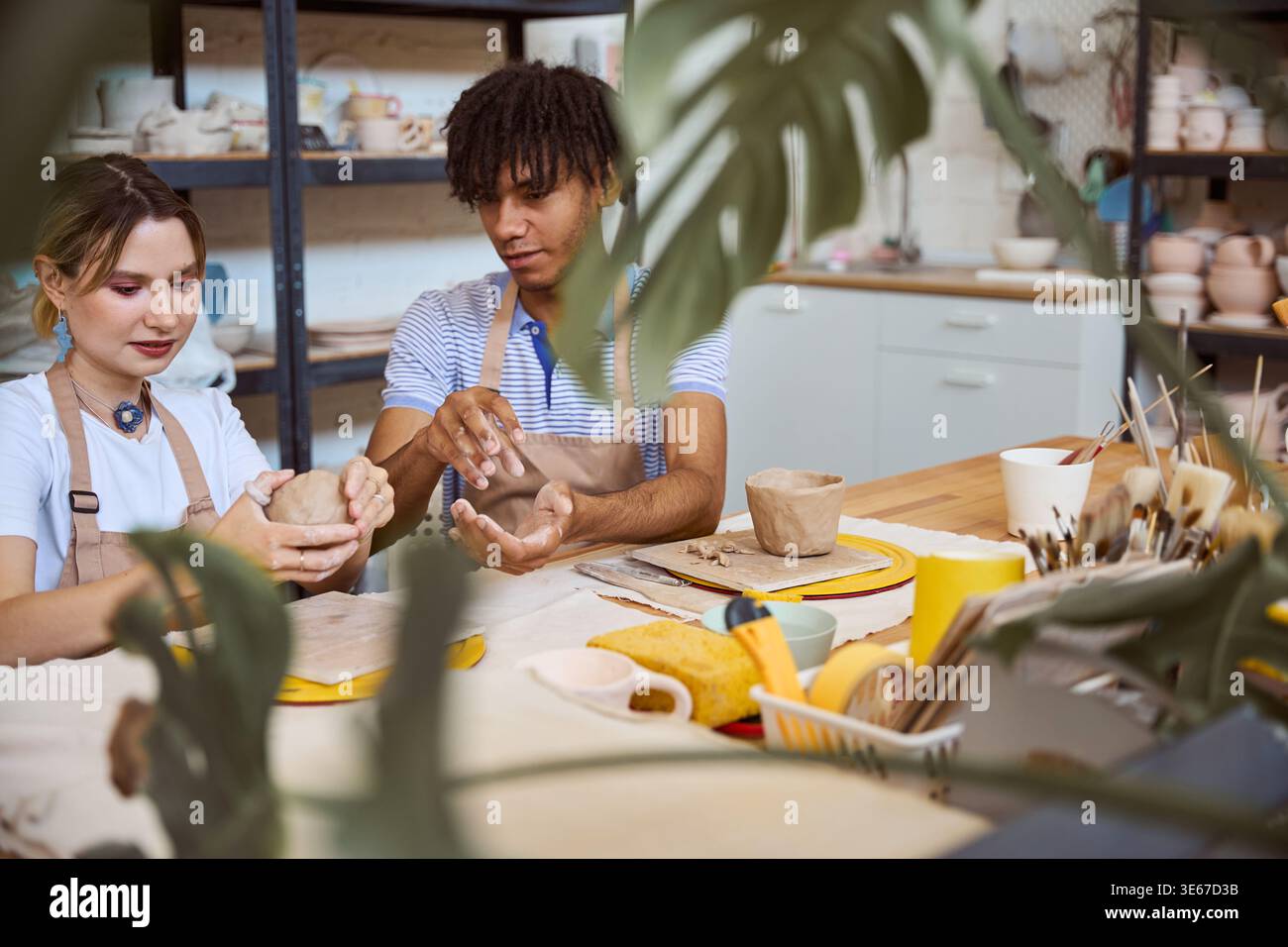 Young adults creating pottery in a bright studio Stock Photo