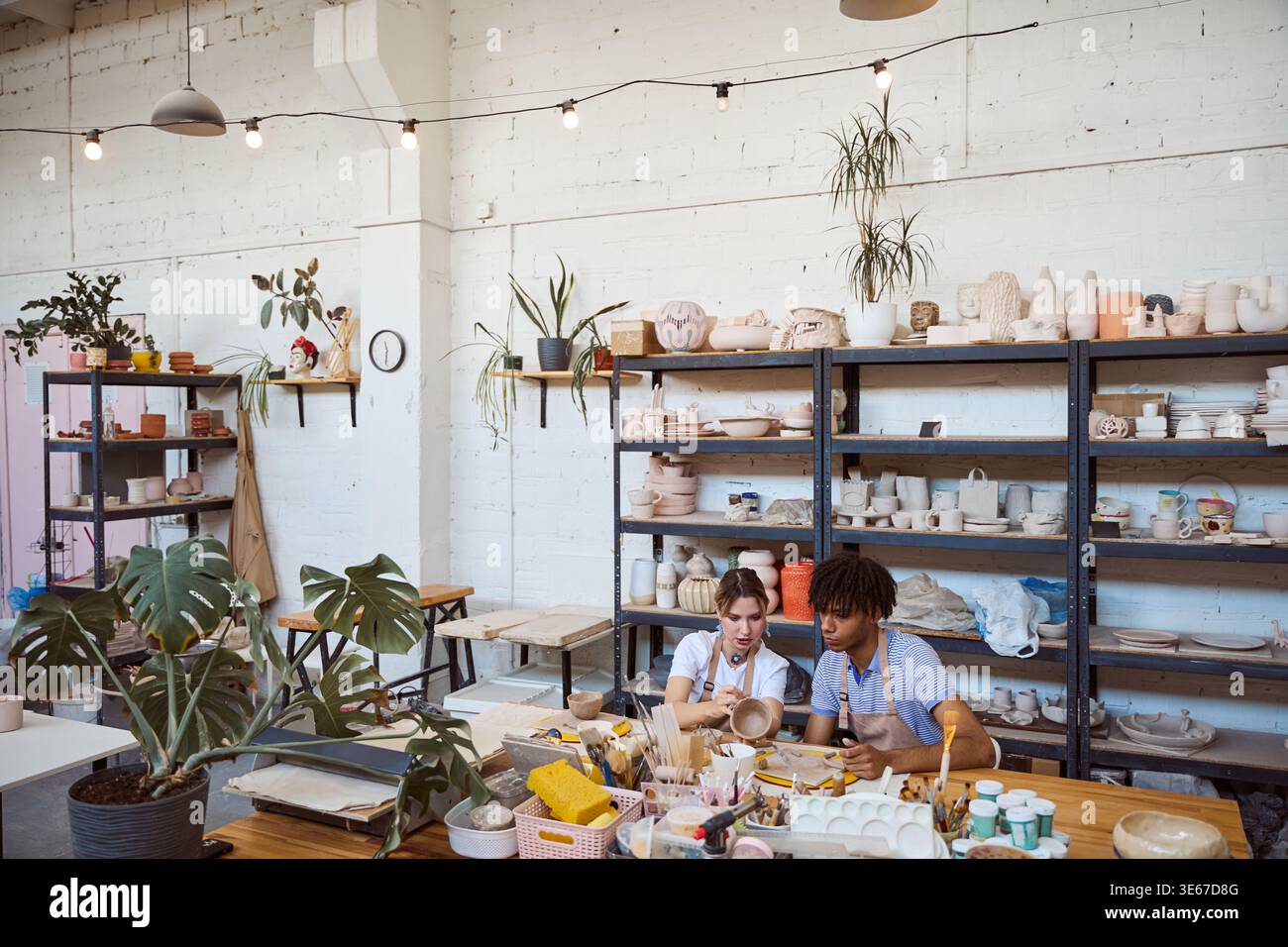 Young adults creating pottery in a bright studio Stock Photo