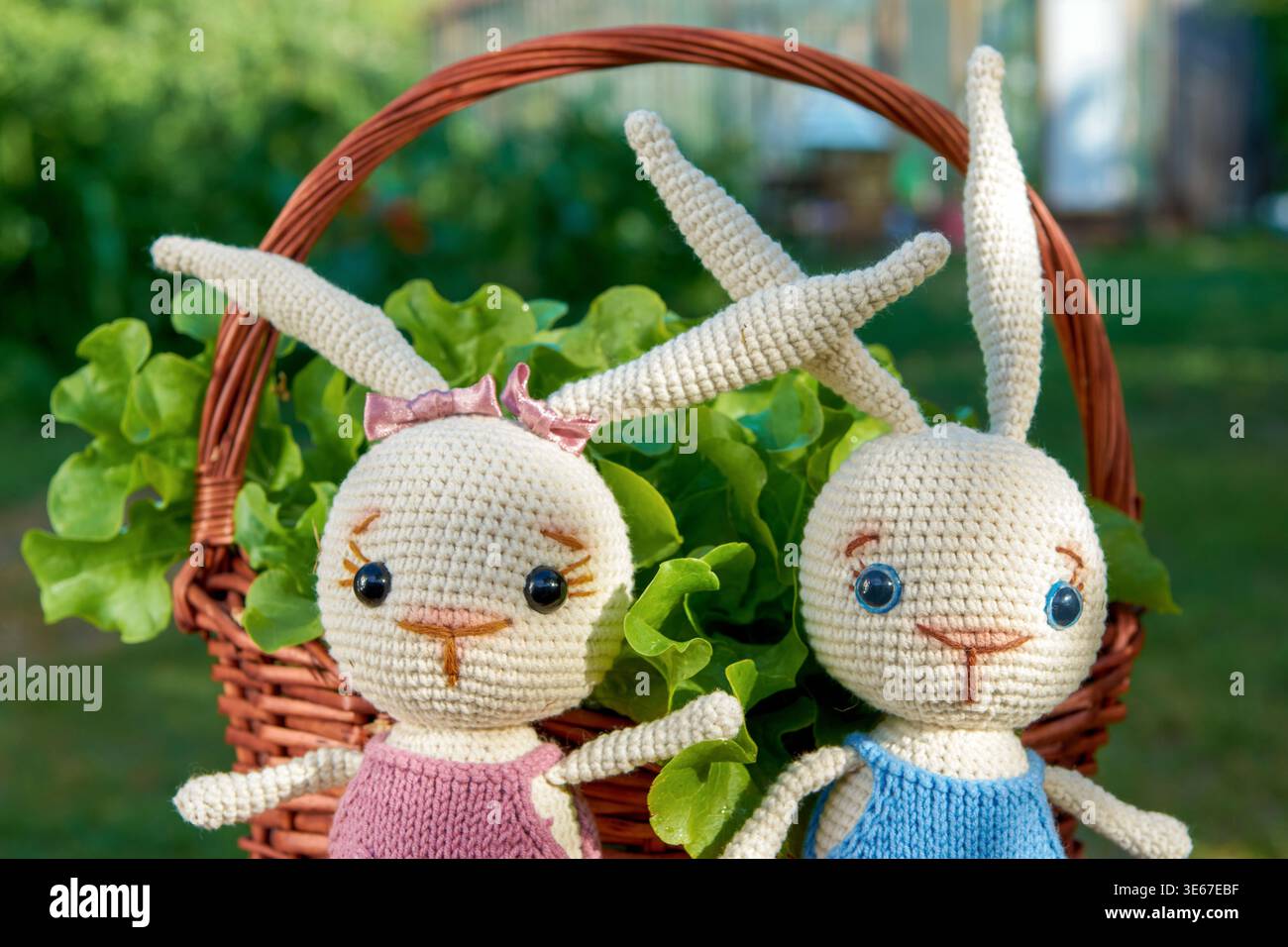 Toy bunnies in a basket with salad on a Sunny summer day Stock Photo