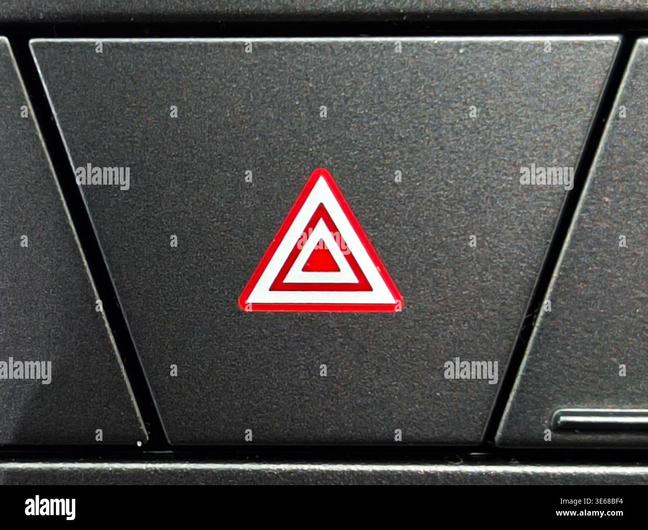 Close up of a red triangle hazard warning flasher button on a modern car dashboard. This essential safety feature is used to alert other drivers durin Stock Photo