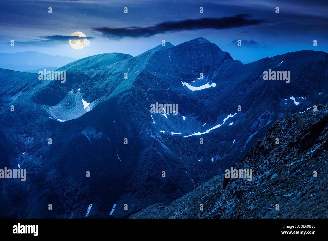 mountain scenery in summer at night. gorgeous mountainous landscape. background with rocky cliffs and grassy hillsides under a cloudy sky. full moon o Stock Photo