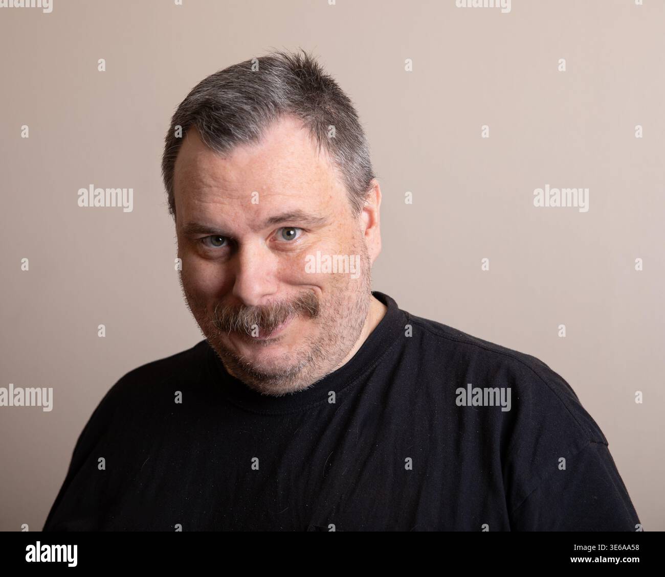 Middle-aged man in black shirt smiles warmly Stock Photo