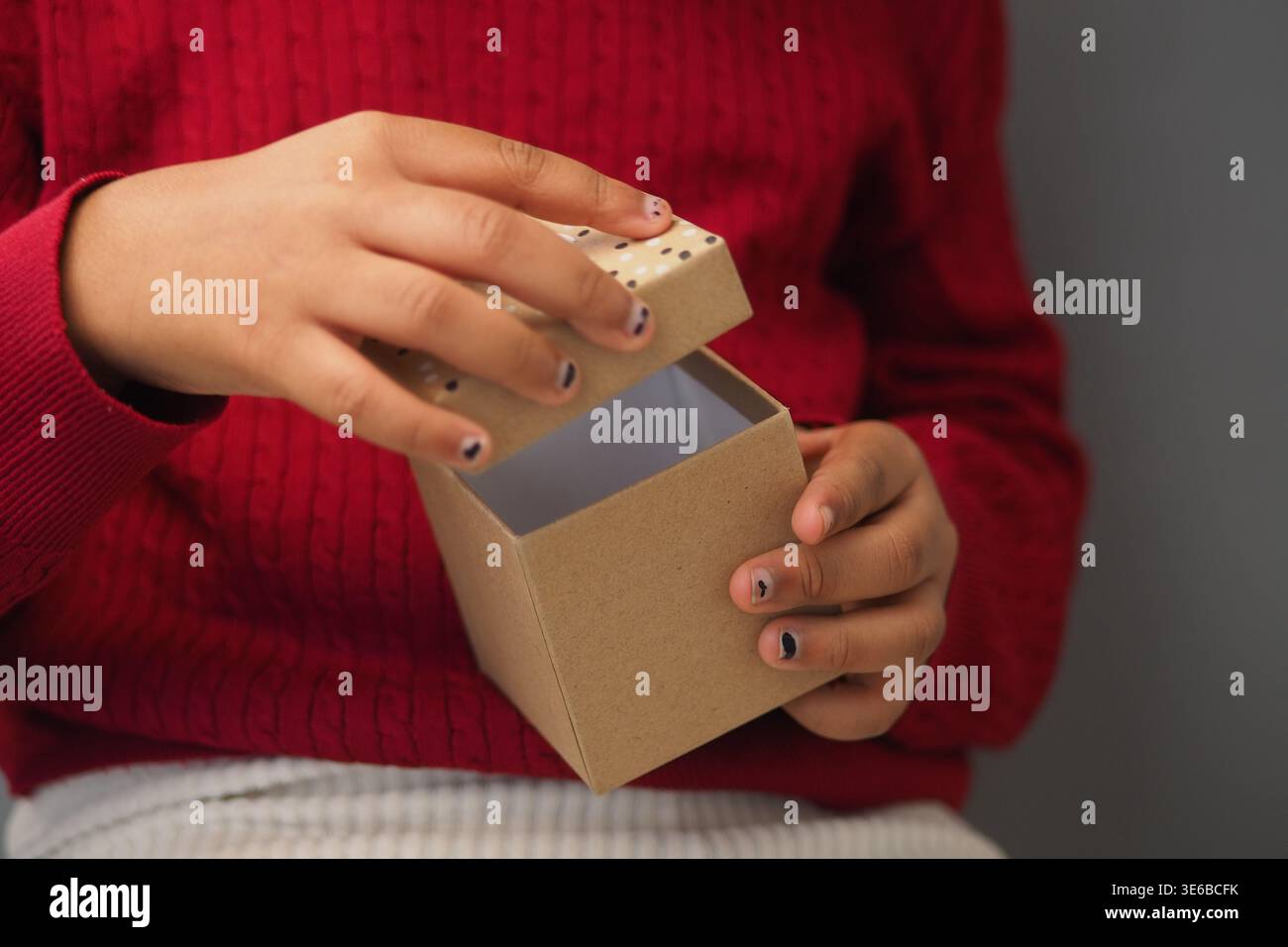Child opens a small box with a brown lid Stock Photo