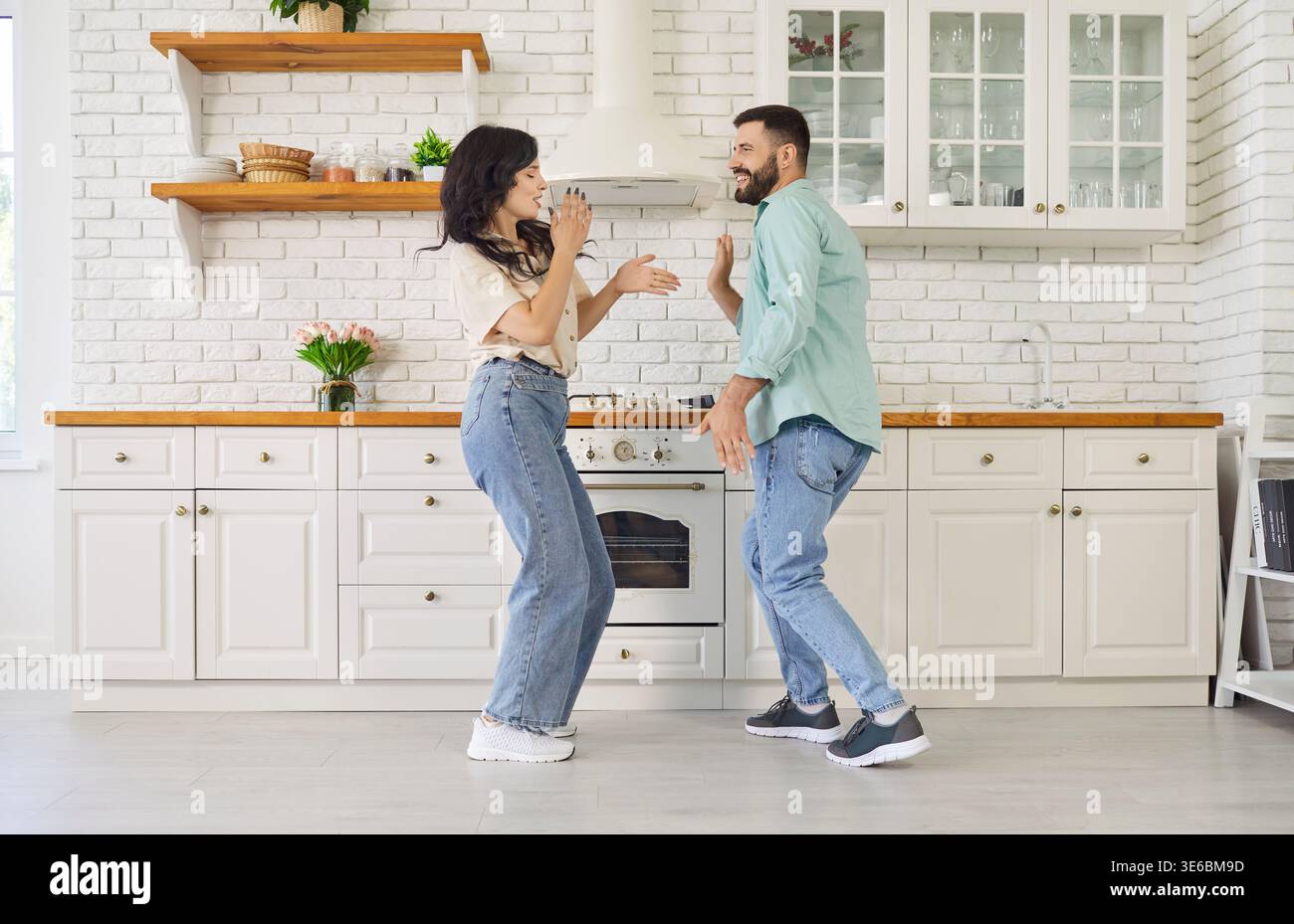Happy carefree couple dancing together in modern kitchen at home, smiling Stock Photo
