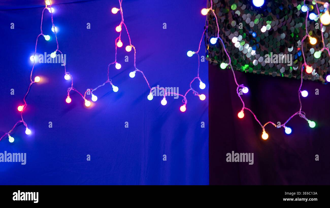 Festive Multi-Colored Globe String Lights on a Blue and Sequin Background Stock Photo