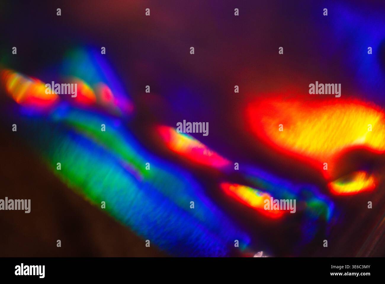 Abstract light patterns display vibrant colors of blue, green, red, and yellow, created by reflections and refractions on a smooth surface Stock Photo