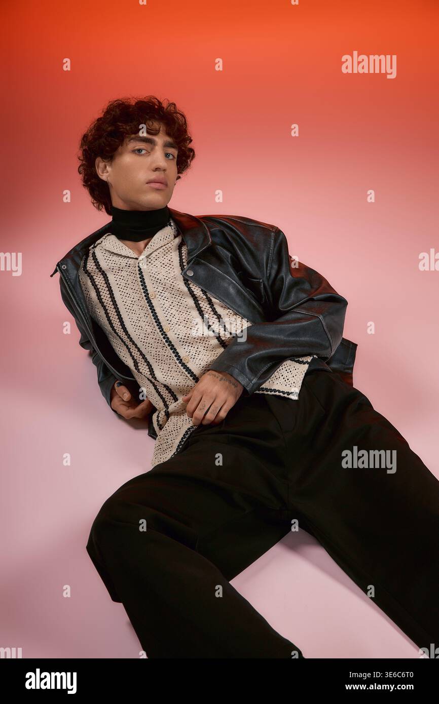 Handsome man relaxes in fashionable attire with a striking background of colors. Stock Photo