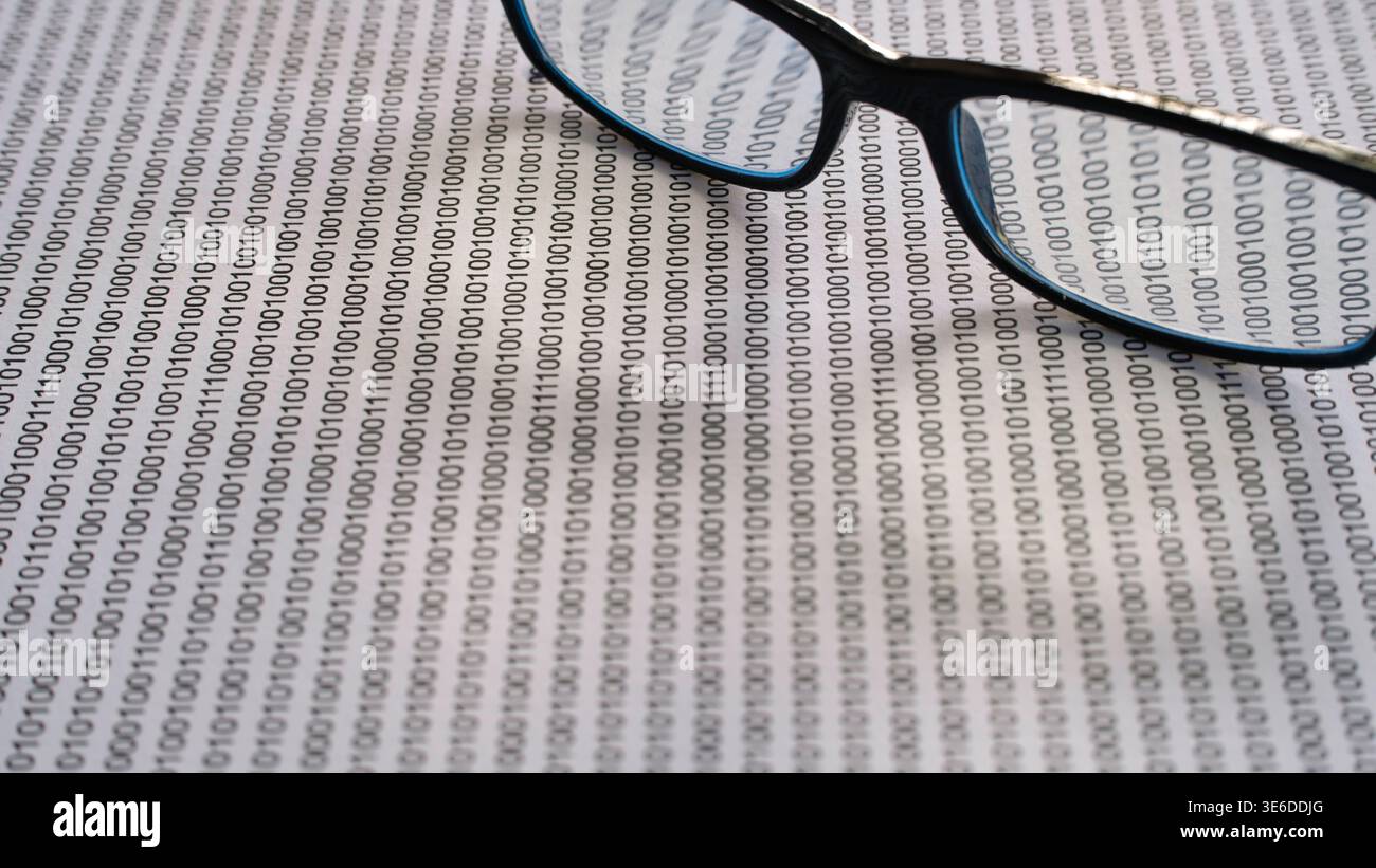 Glasses on binary code background representing data privacy and cybersecurity analysis. Stock Photo