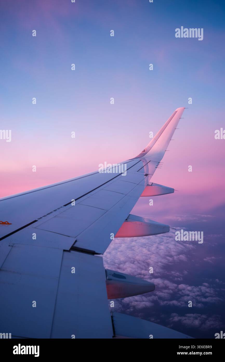 Airplane wing during sunset above clouds Stock Photo