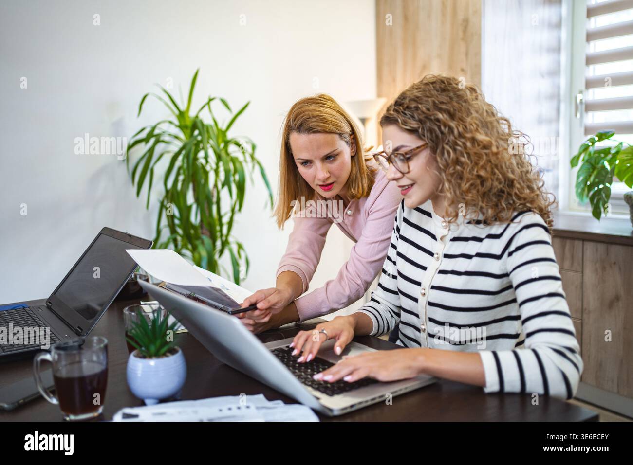 Two female colleagues working together on business report Stock Photo