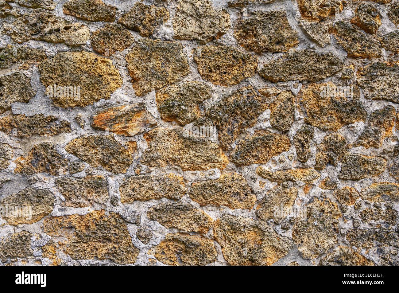 Rough textured stone wall with visible mortar and weathered surfaces Stock Photo