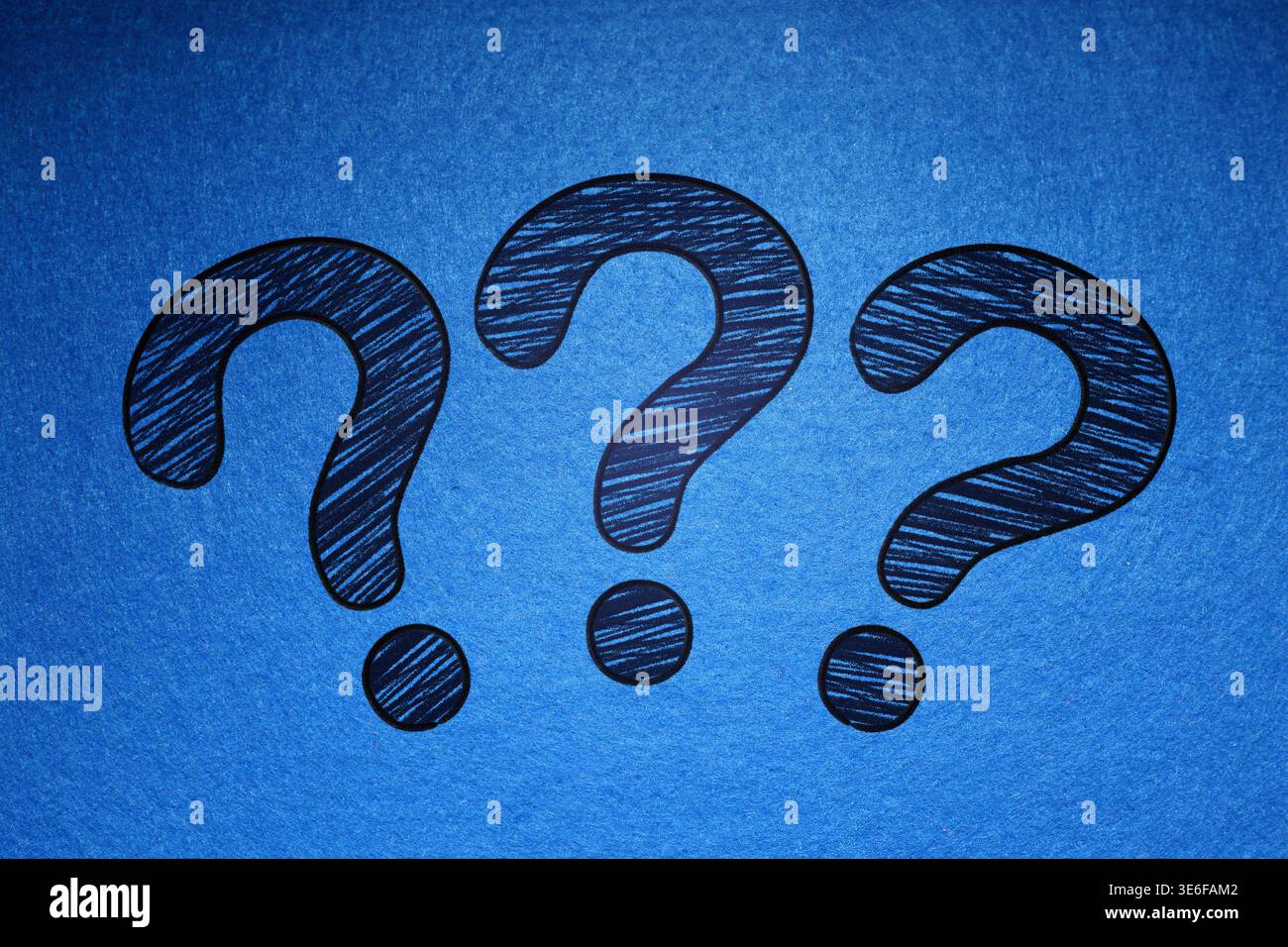Three question marks drawn on blue background Stock Photo