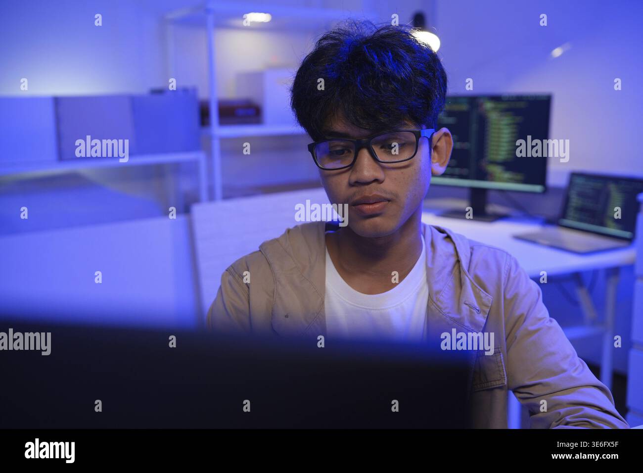Male Software Engineer Writing Code on Desktop Computer with Multiple Screens Setup. Data center programmer managing large datasets used in AI trainin Stock Photo
