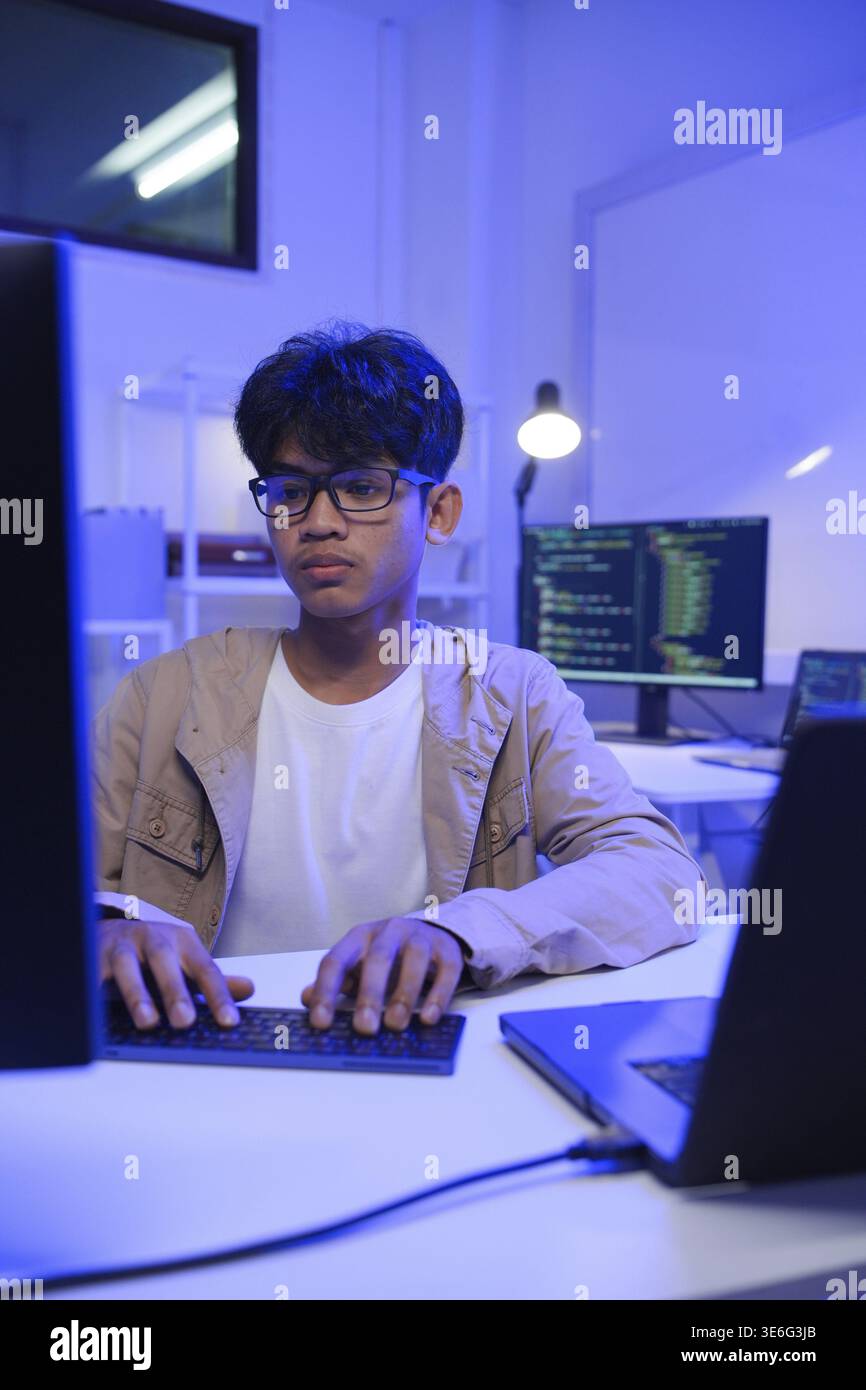 Male Software Engineer Writing Code on Desktop Computer with Multiple Screens Setup. Data center programmer managing large datasets used in AI trainin Stock Photo