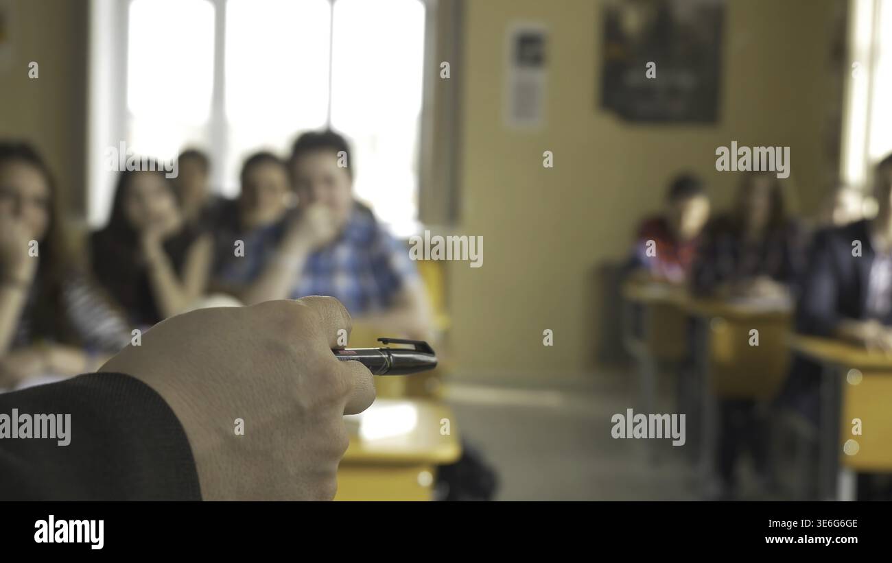Teacher with a group of high school students in classroom. View from the hands of the teacher explaining the lecture Stock Photo