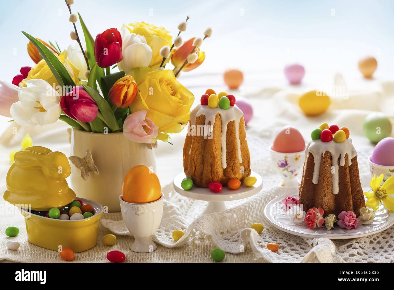 Easter table setting with spring flowers, cakes and easter eggs Stock Photo